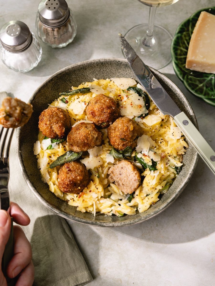 Une bouchée de boulette de poulet maison avec un orzotto crémeux au parmesan, des épinards et de la sauge croustillante.