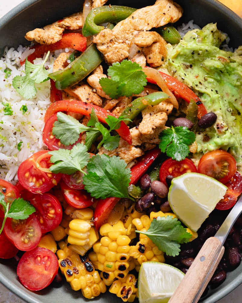 Bol de fajita poulet et poivron avec du guacamole, des tomates, des haricots noirs et du maïs