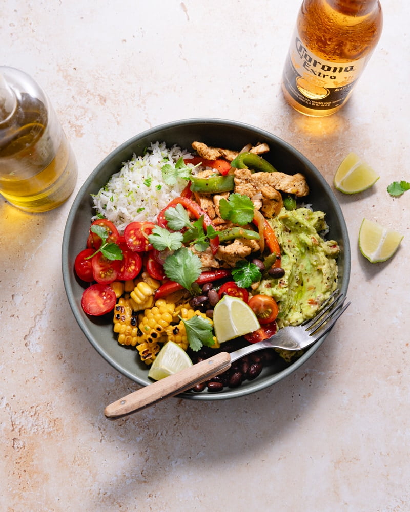 Bol de fajita poulet et poivron avec du guacamole, des tomates, des haricots noirs et du maïs