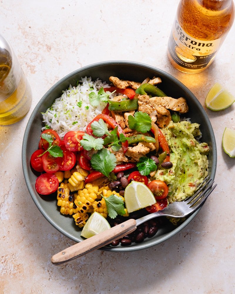 Bol de fajita poulet et poivron avec du guacamole, des tomates, des haricots noirs et du maïs