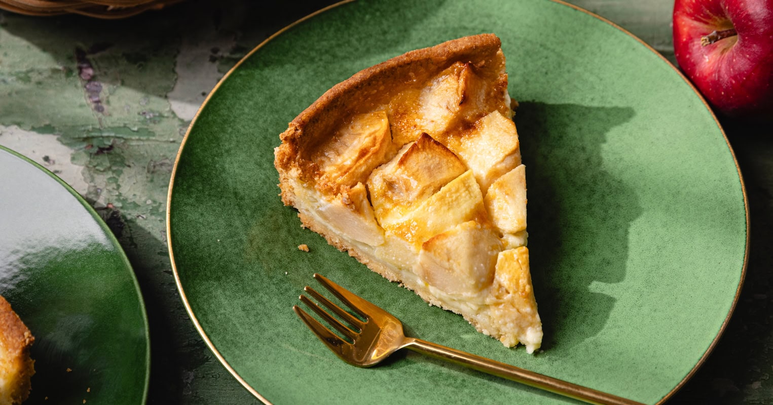 Une part de tarte normande aux pommes sur une assiette