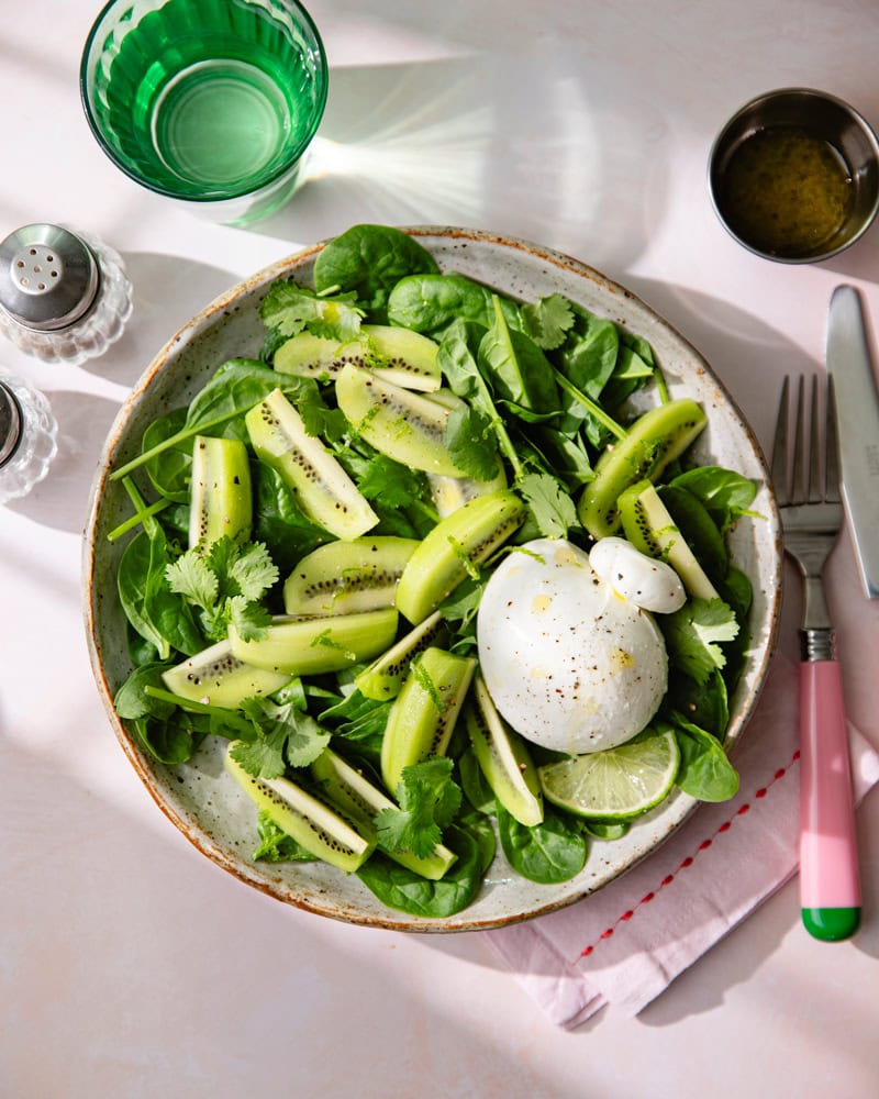 Assiette de salade de feuille d'épinard, burrata et kiwi