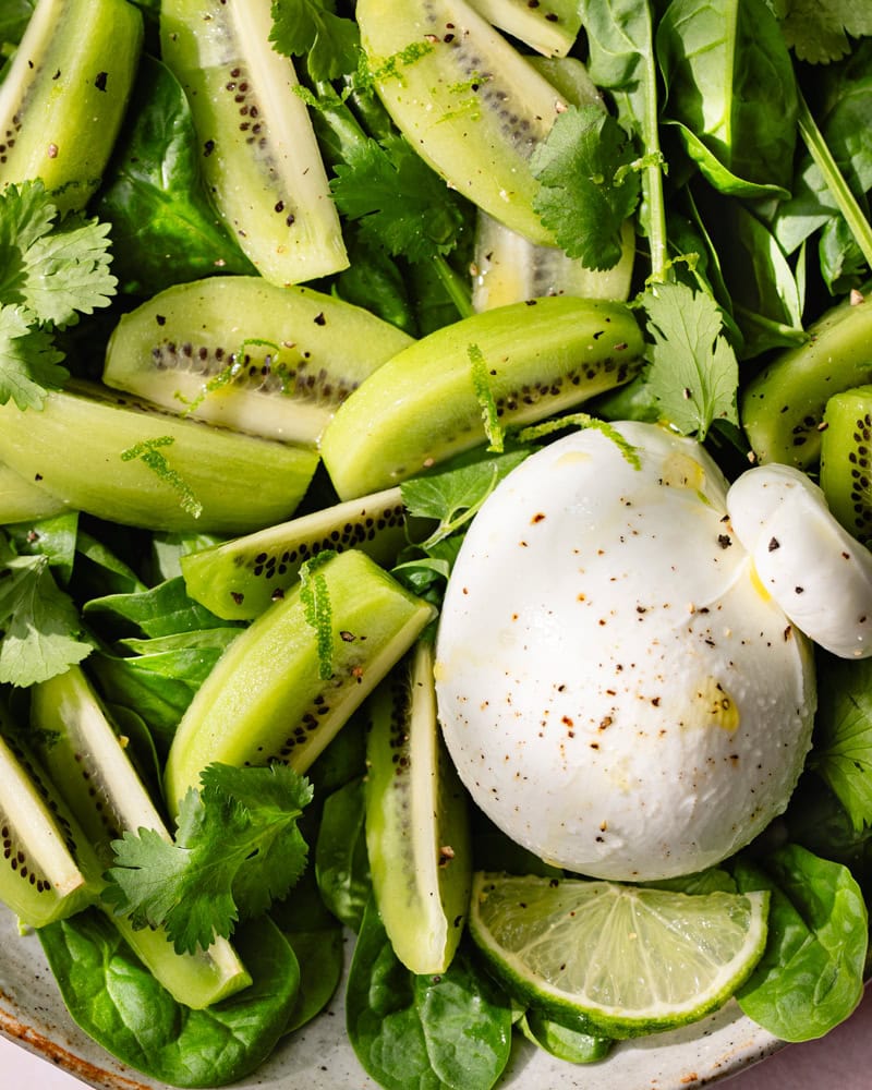 Assiette de salade de feuille d'épinard, burrata et kiwi