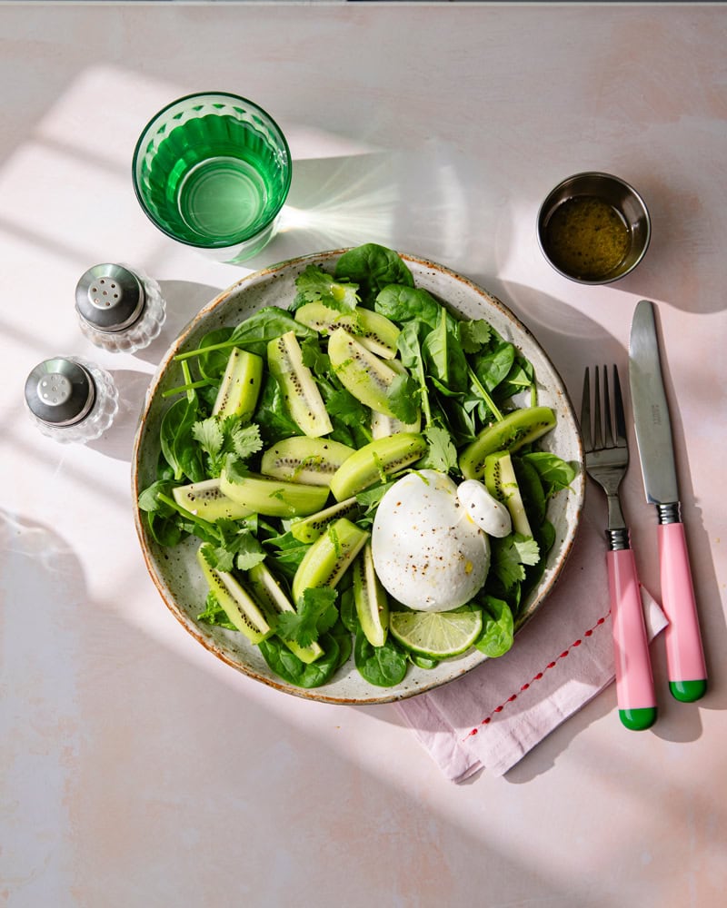 Assiette de salade de feuille d'épinard, burrata et kiwi