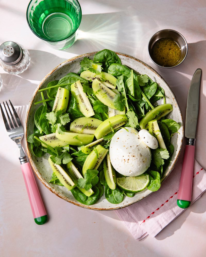 Assiette de salade de feuille d'épinard, burrata et kiwi