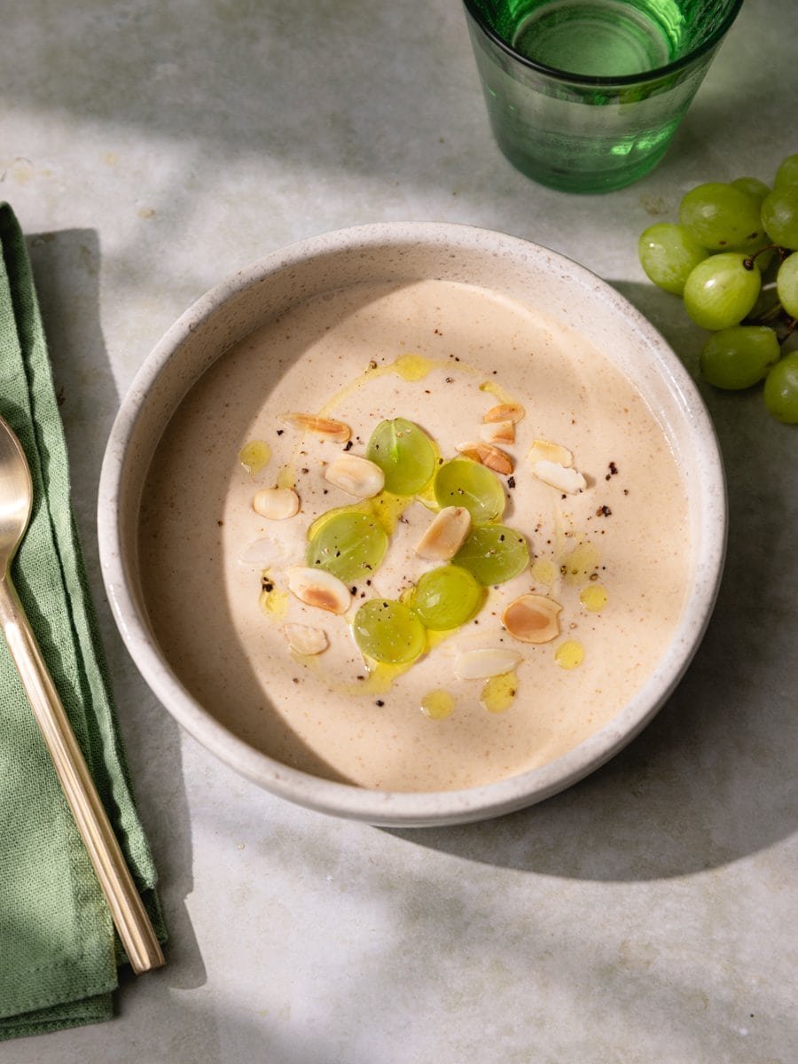 Bol de soupe froide ajo blanco garni de raisins verts et d’amandes effilées