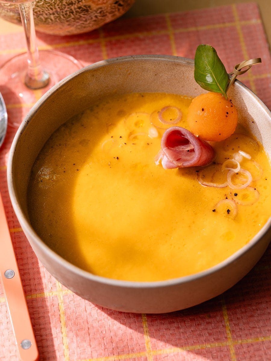 Bol de gaspacho au melon décoré de jambon cru, de melon et de basilic frais