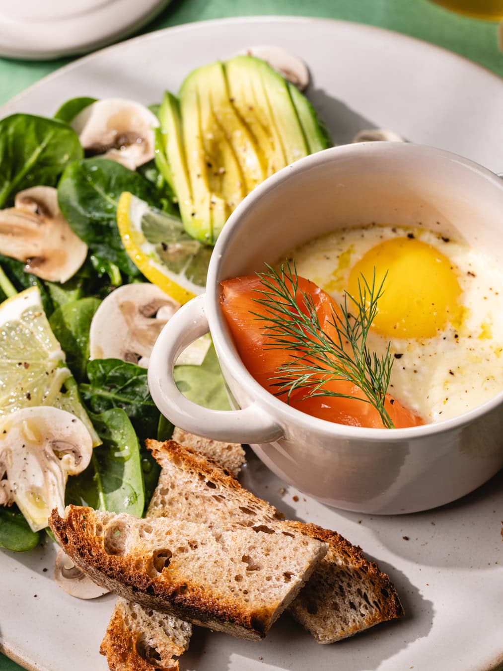 Assiette de petit déjeuner avec des œufs cocotte au saumon, une salade et du pain au levain