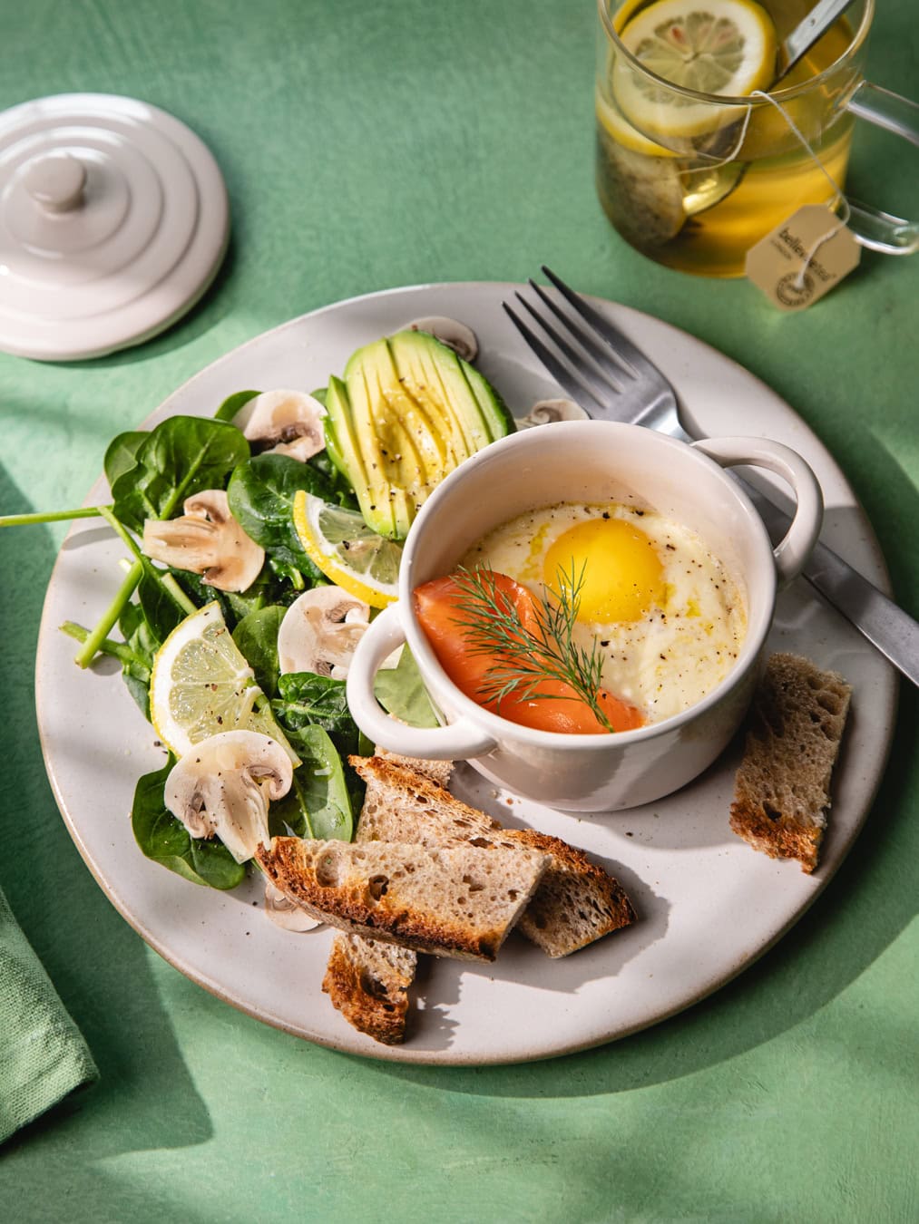 Assiette de petit déjeuner avec des œufs cocotte au saumon, une salade et du pain au levain