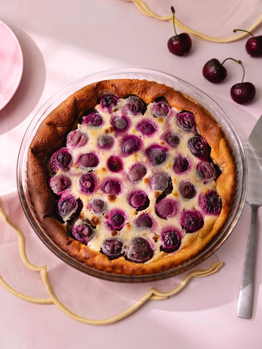 Clafoutis aux cerises moelleux dans un plat à tarte, avec cerises entières légèrement caramélisées et pâte dorée maison