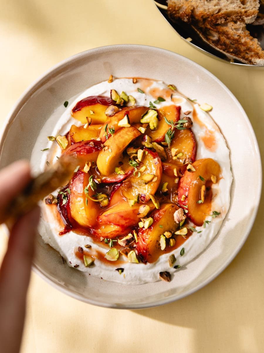 Assiette de cottage cheese fouetté avec pêches caramélisées, pistaches et thym