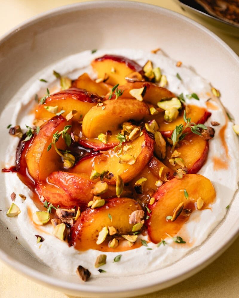 Assiette de cottage cheese fouetté avec pêches caramélisées, pistaches et thym
