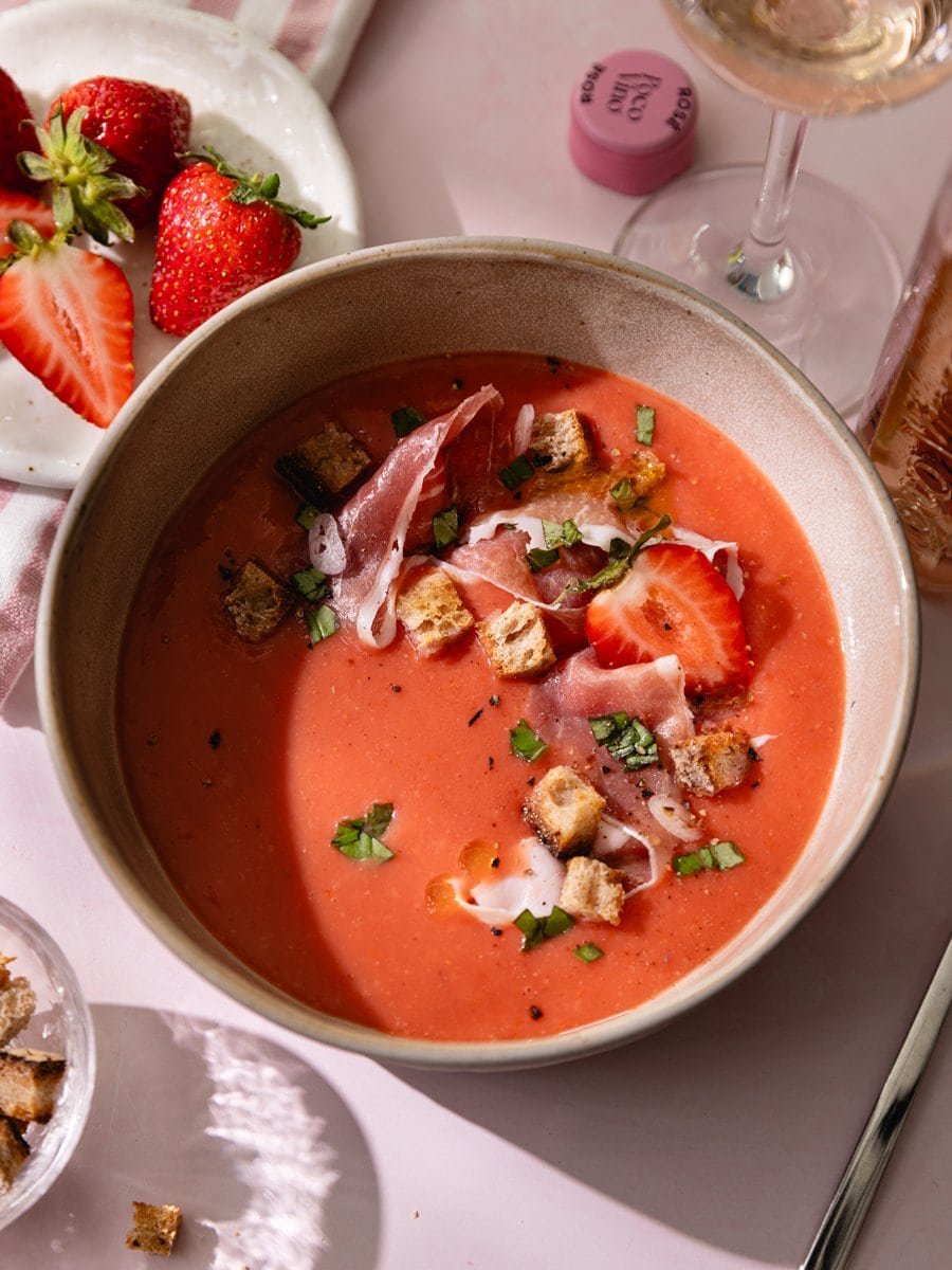 Bol de gaspacho tomates fraises accompagné de fraises fraîches et d'un verre de vin rosé