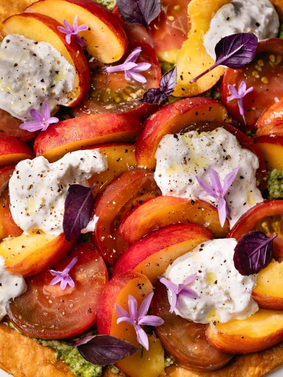 Tarte fine aux tomates anciennes et pêches garnie de stracciatella et pesto maison