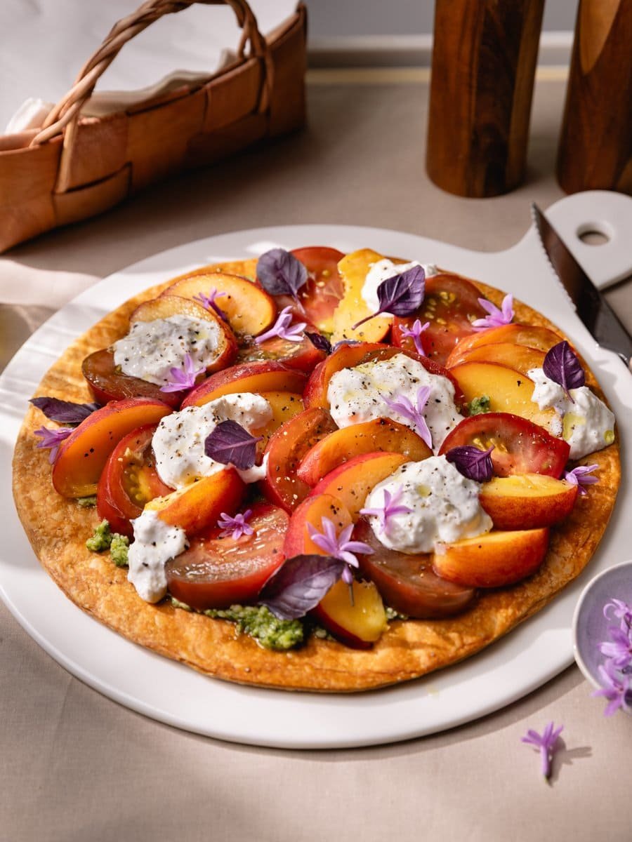 Tarte fine croustillante aux tomates anciennes, pêches fraîches, pesto et stracciatella