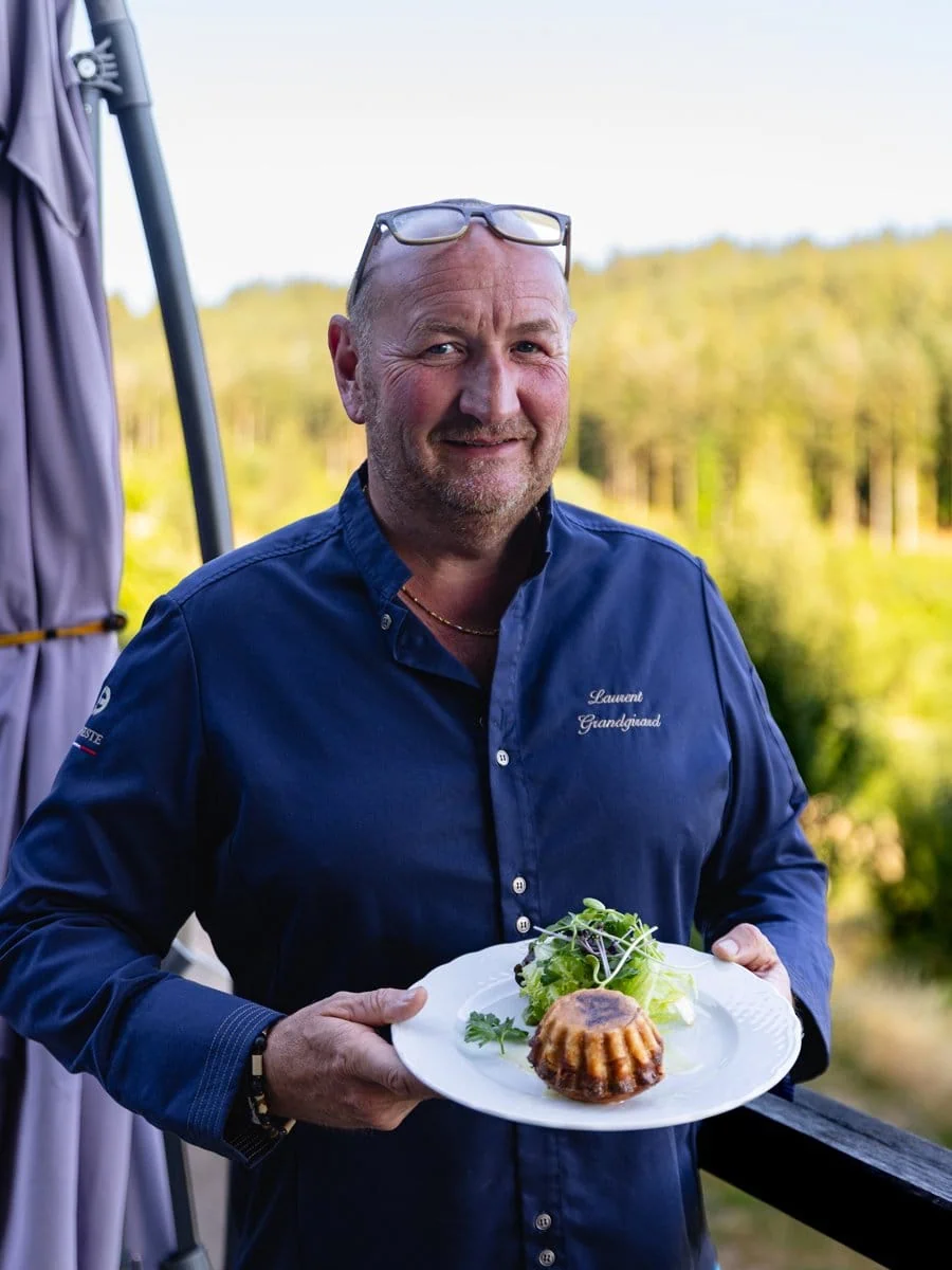 Portrait du chef Laurent Grandgirard tenant une assiette devant La Vigotte